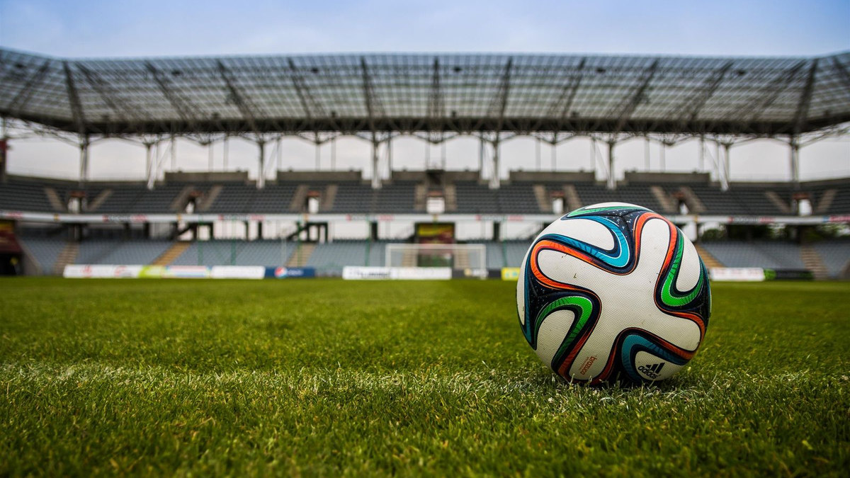 Ballon de football au premier plan, pelouse et stade flous