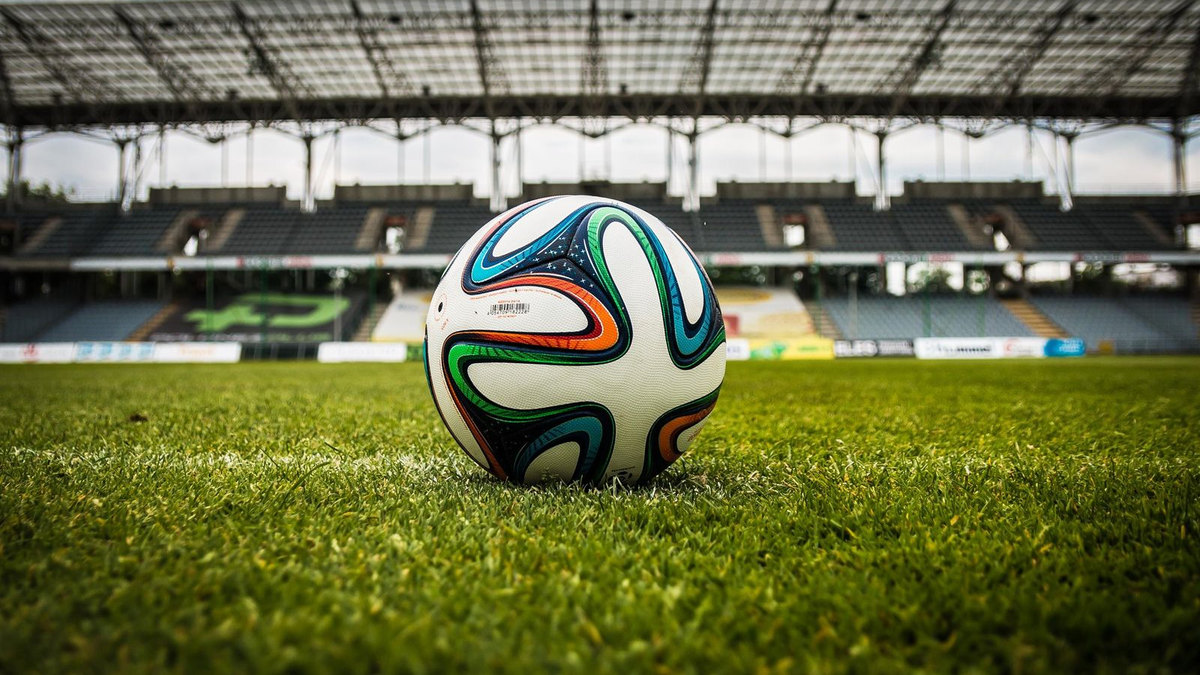 Ballon de football sur la pelouse, but flou en fond
