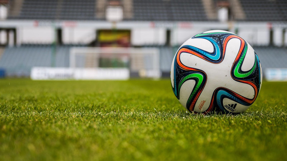 Ballon de football sur la pelouse, stade en fond